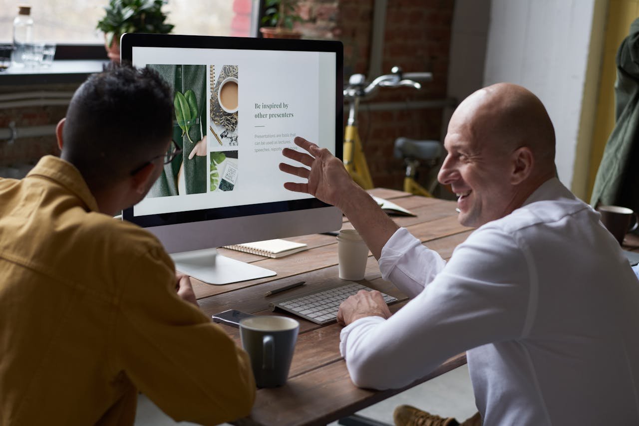 About Two professionals collaborating in a modern workspace, discussing a project on a computer screen.